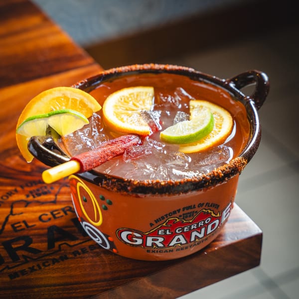 A large El Cerro Grande Mexican Restaurant drink with citrus slices and a chili straw.