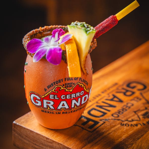 El Cerro Grande Mexican Restaurant's drink in a branded clay mug, garnished with fruit and a flower.