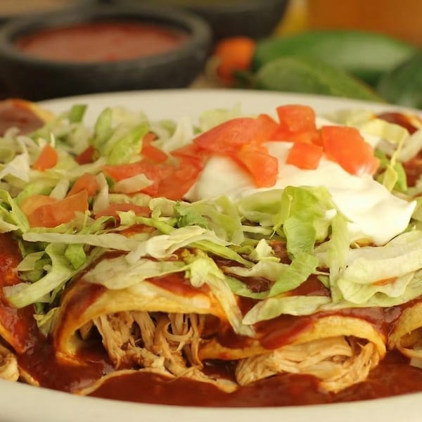 Close-up of El Cerro Grande's enchiladas topped with red sauce, shredded lettuce, diced tomatoes, and sour cream.