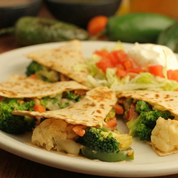 Vegetable quesadillas with broccoli, cauliflower, and bell peppers, served with lettuce, tomato, and sour cream.