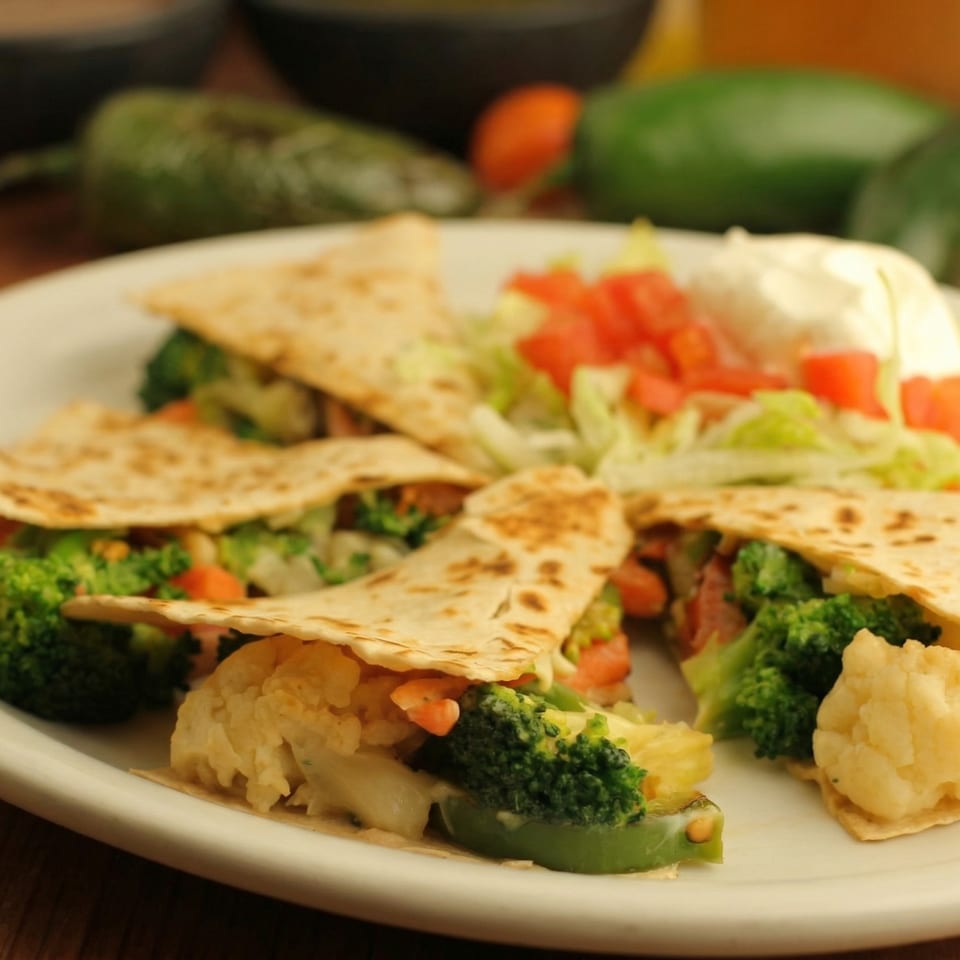 Vegetable quesadillas with broccoli, cauliflower, and bell peppers, served with lettuce, tomato, and sour cream.
